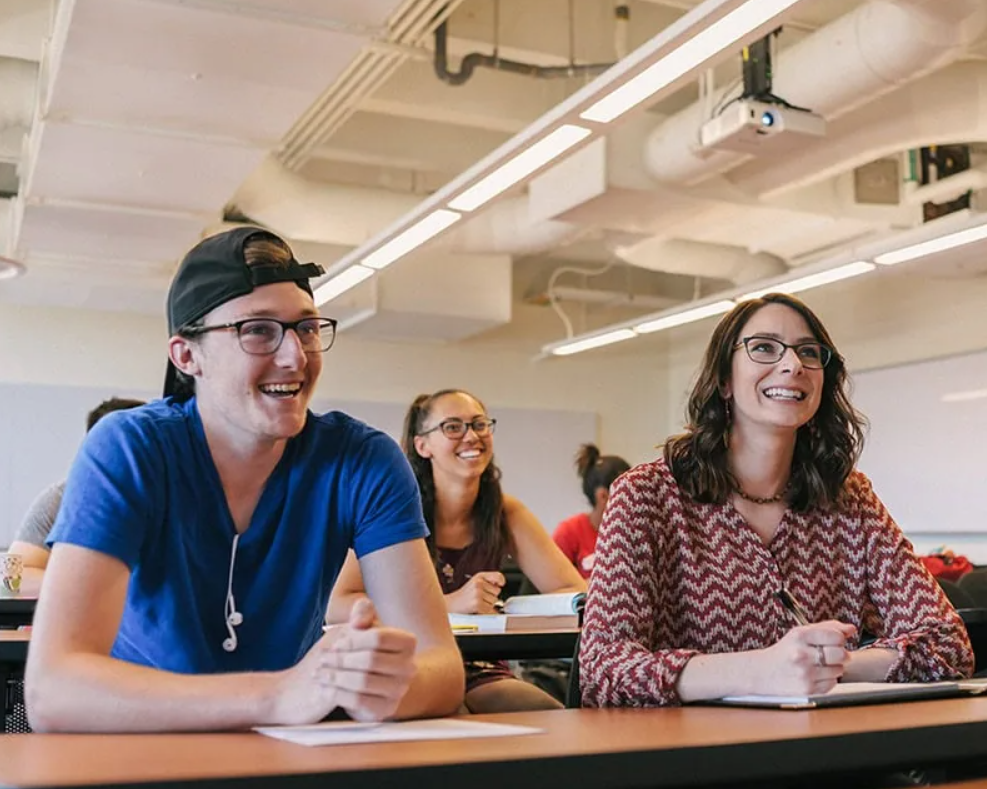 a group of smiling students seated at tables